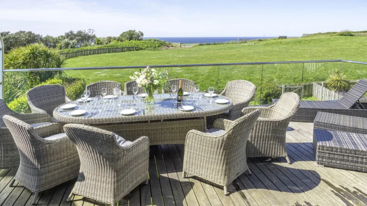 Villa 27 balcony. Dining table and chairs. Sun lounges. View of the Tennis court lawn and ocean.